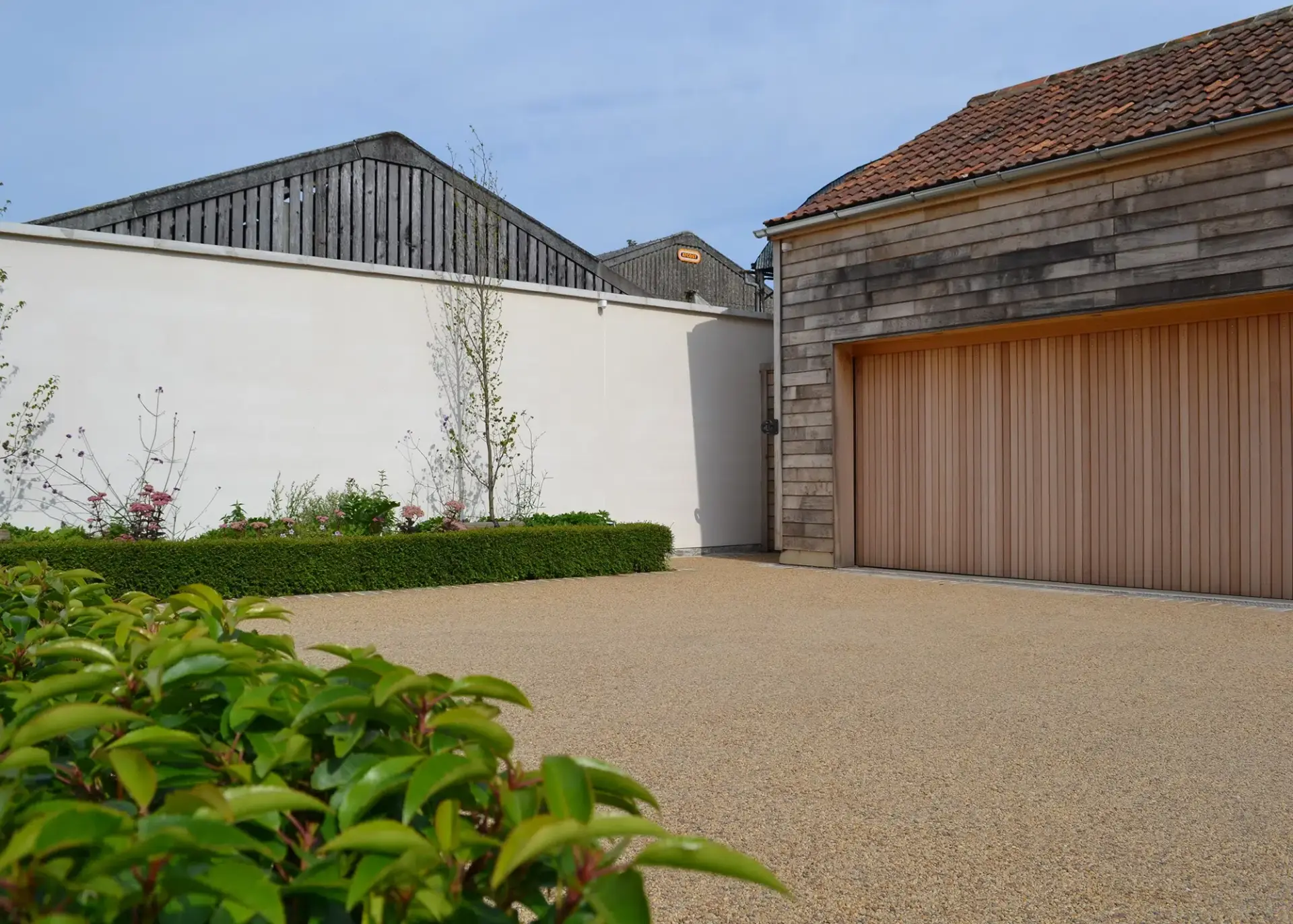 Resin bound gravel driveway laid to a smooth finish beside a timber-clad garage